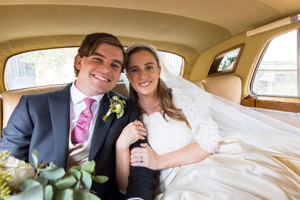 bride and groom in the back of a wedding car