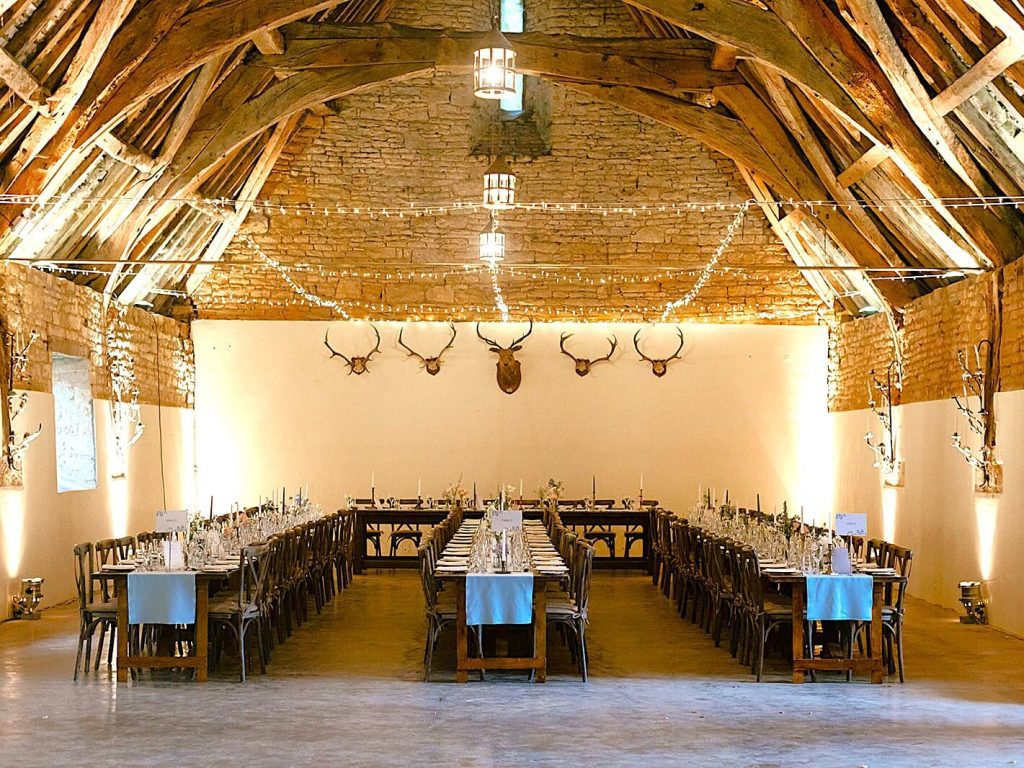 Inside the Tithe Barn at Stanway House with tables set up for wedding breakfast