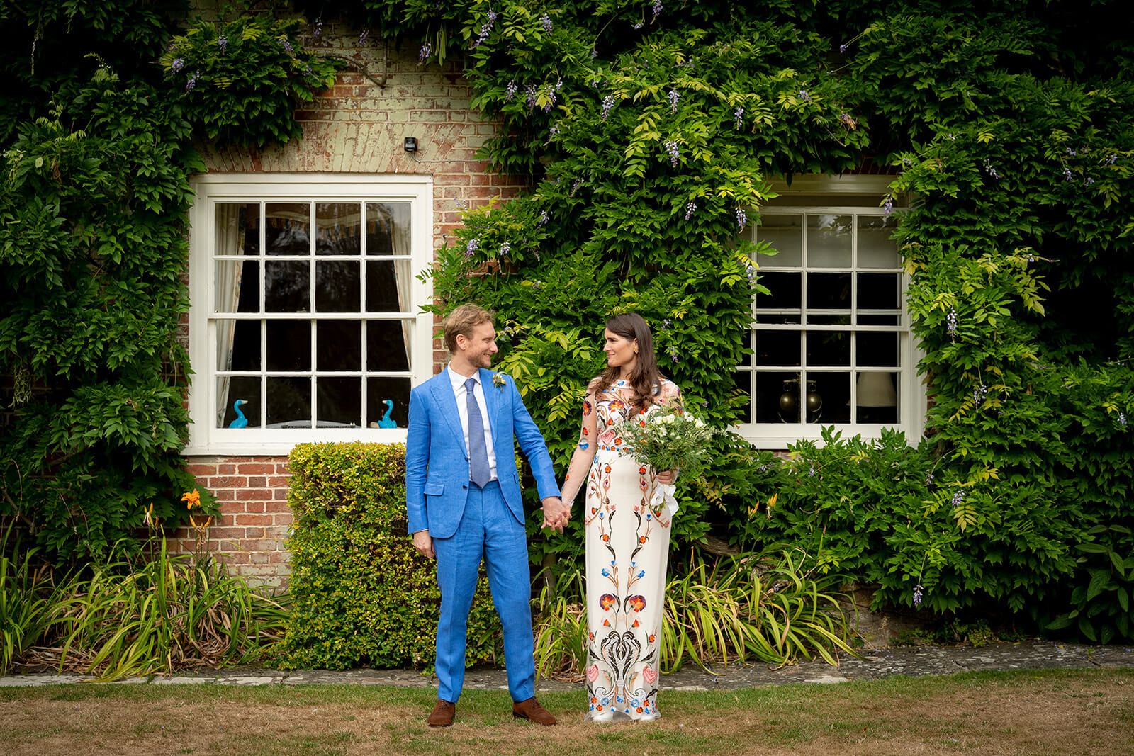 Wiltshire Wedding Planner Country House Bride and groom holding hands outside ivy-covered Wiltshire country house during at home garden wedding