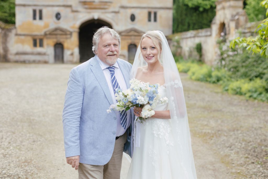 bride in white with long veil and father of the bride with blue linen jacket and chinos for a garden wedding