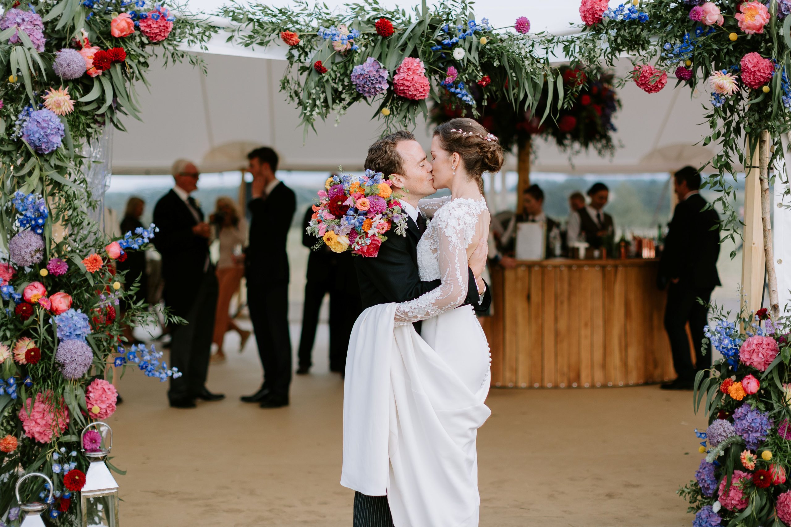 How to Plan a Wedding in 6 Months Stress-Free Tips from a UK Wedding Planner Couple kissing at marquee entrance bride and groom kissing surrounded by pink flowers marquee wedding planner