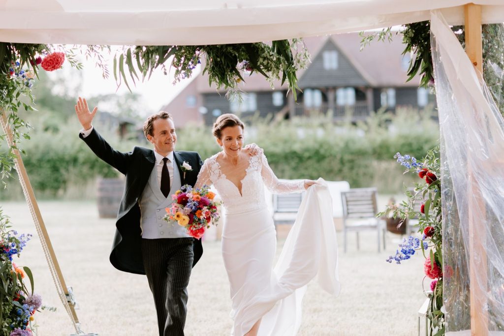 bride and groom celebrating walking into a marquee wedding