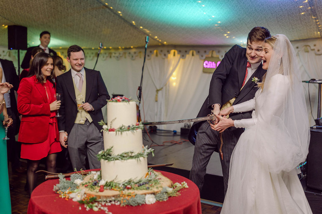 bride and groom cutting the cake with a sword at Welford Park wedding in Berkshire
