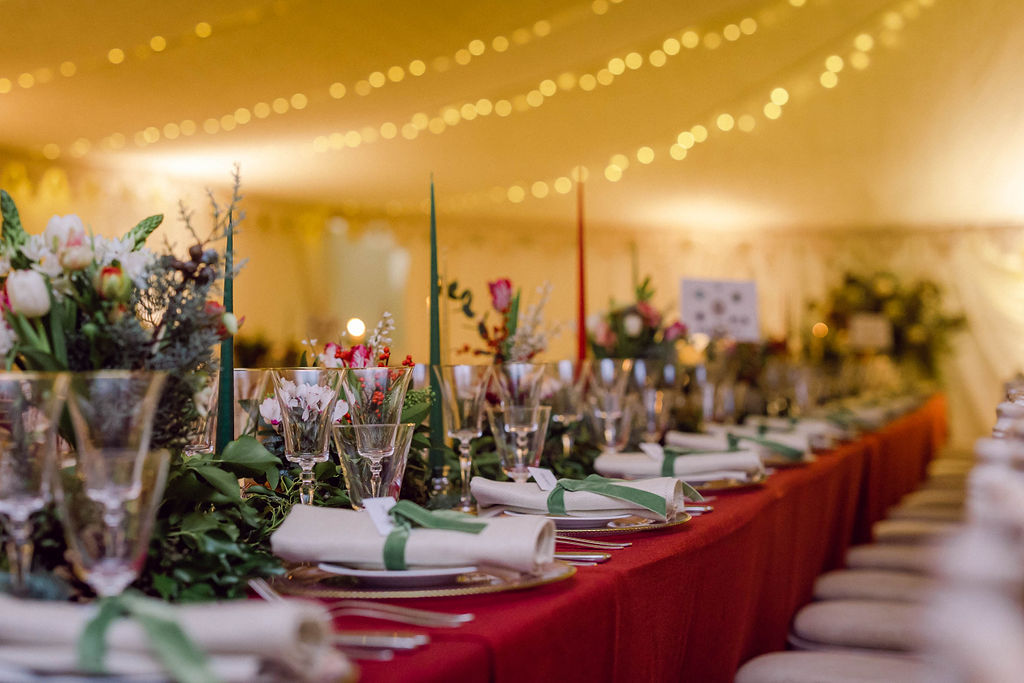 sparkly fairy lights over red and green tables for Christmas marquee wedding in Berkshire styled and planned by Honour & Pop