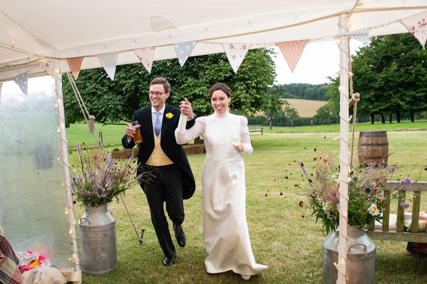 bride and groom entering wedding marquee with bunting